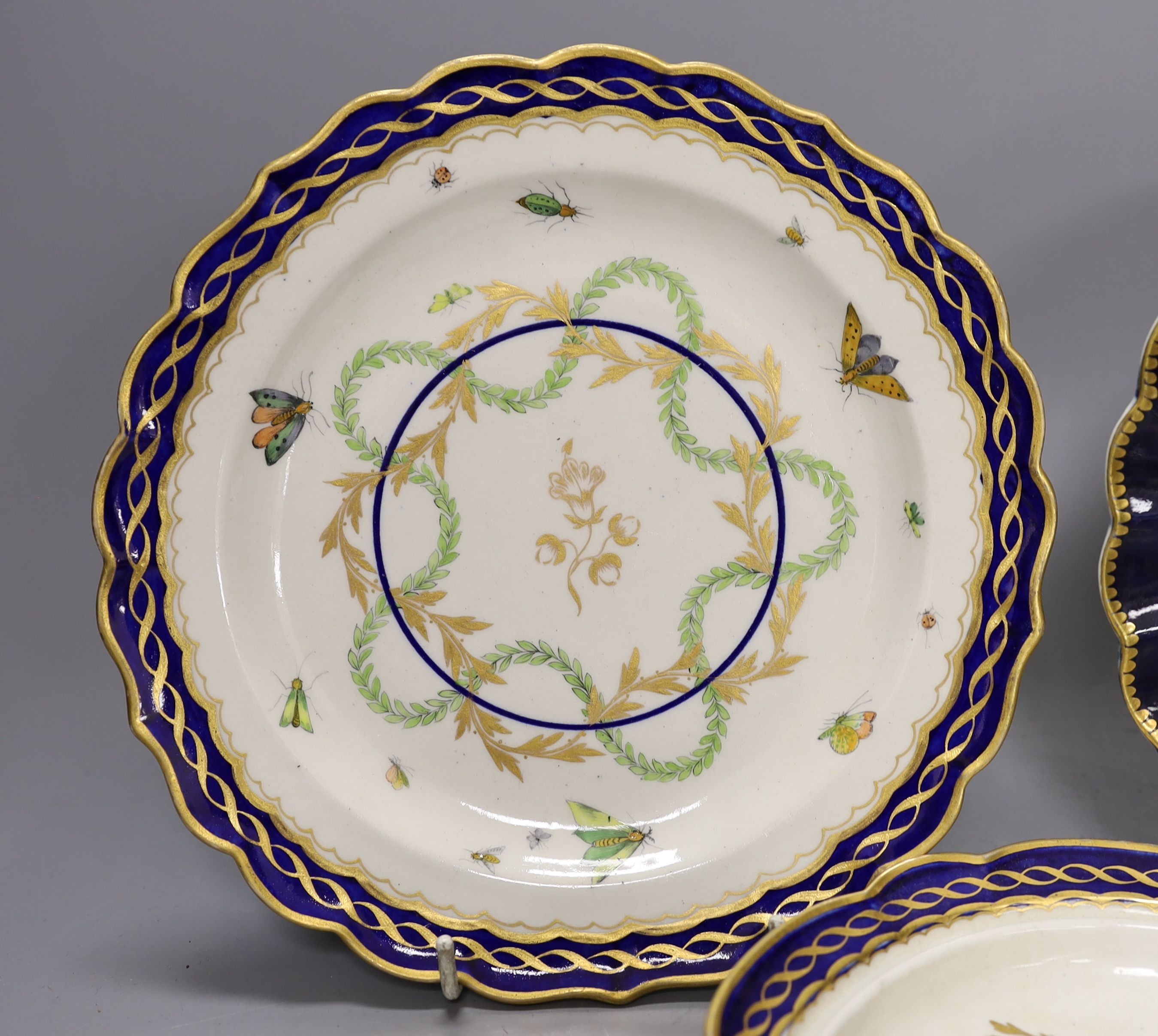 Three Worcester plates having blue border, one with elaborated gilding enclosing a bouquet of flowers, two plates both with a star shaped foliate design in the centre, c.1775, largest 21.5 cm